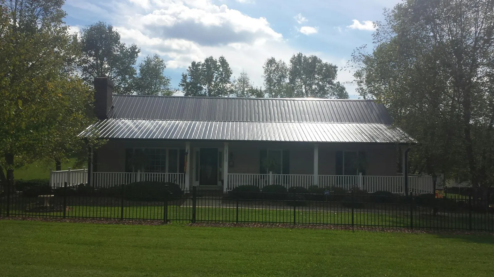 Gray metal roof on a brick ranch with a full width front porch — Gutter Guard Installation work by our crew in Hot Springs