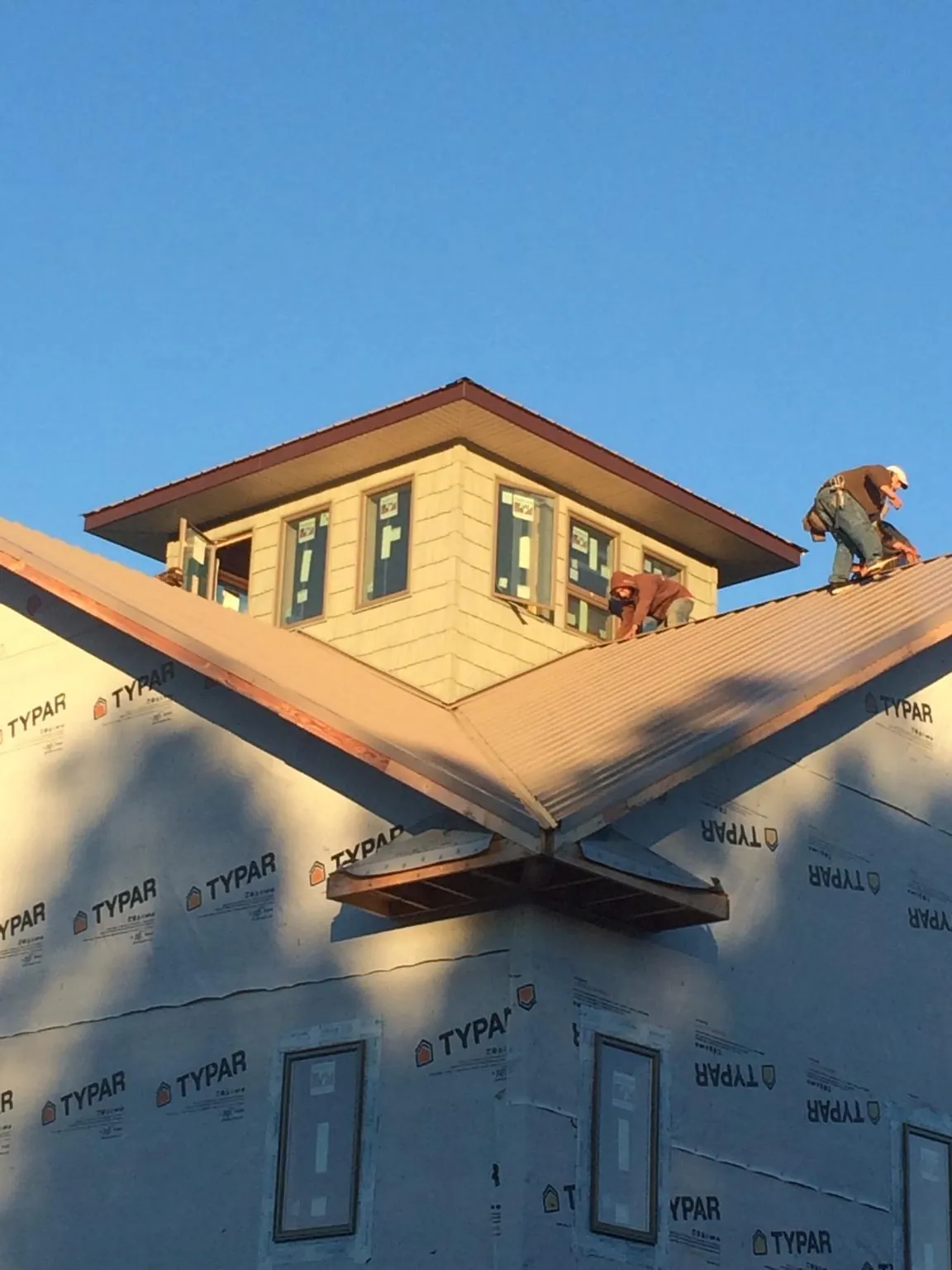 Roofers working around a rooftop cupola on a new metal roof at sunset — Roof Waterproofing in Hot Springs by Roofing Brothers